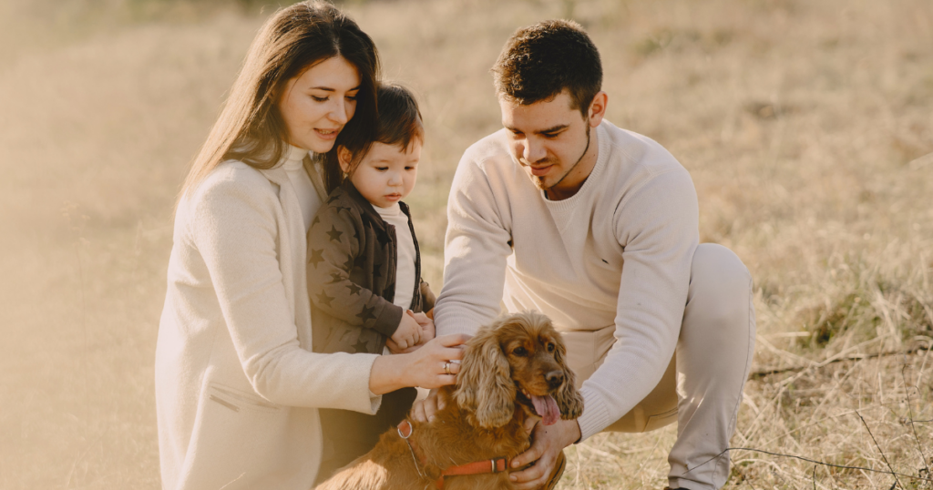 Family with a young child and dog spending time together outdoors, illustrating the trust, love, and security that help strong families grow.